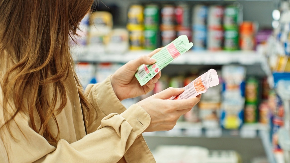 Shopper comparing product labels while choosing packaged goods in a grocery store