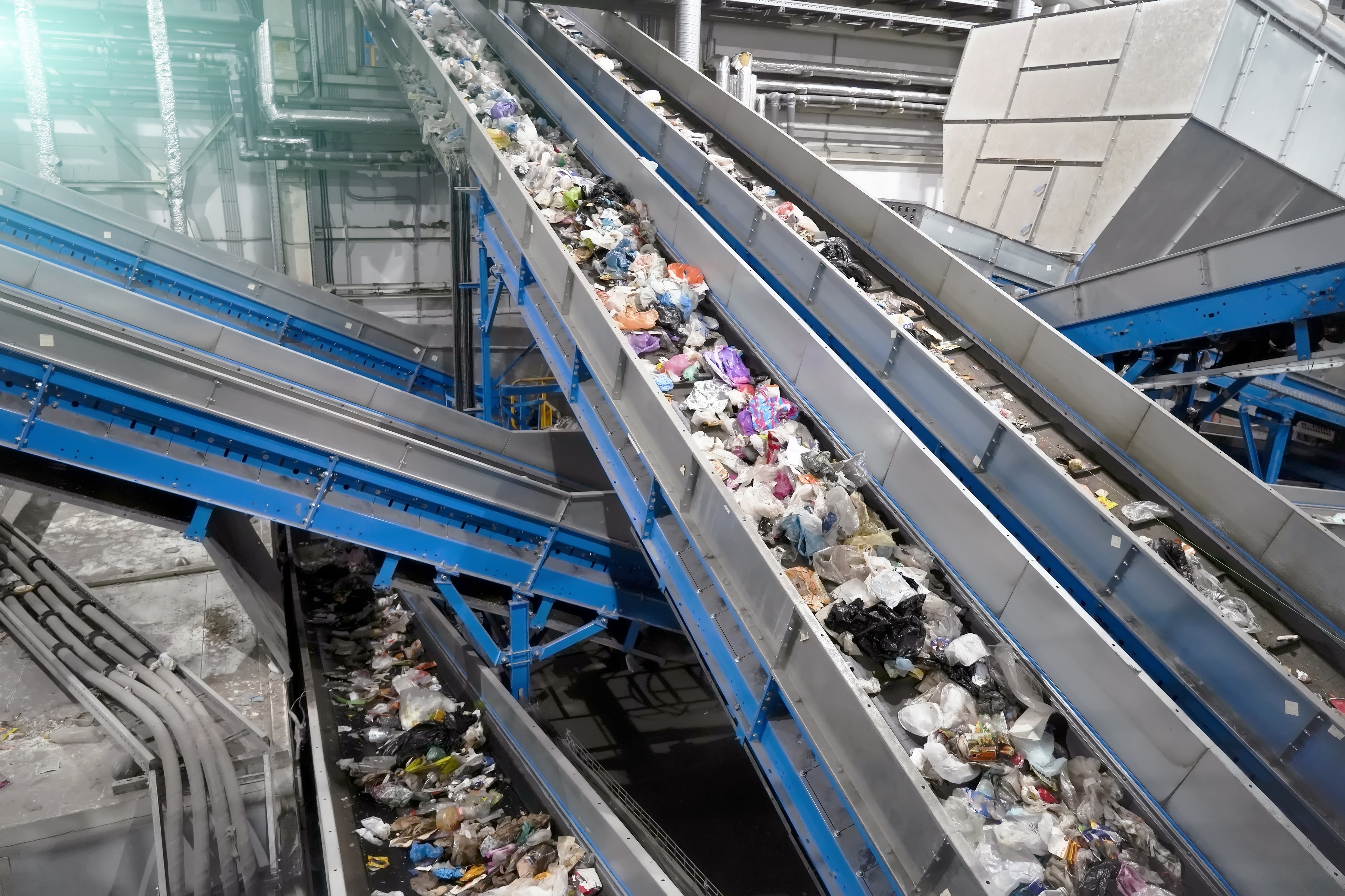 Multiple conveyor belts transport recyclable plastic materials through an industrial recycling facility.
